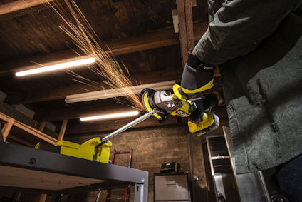 Person som använder en vinkelslip i ett träförråd, gnistor flyger från metallen som bearbetas.