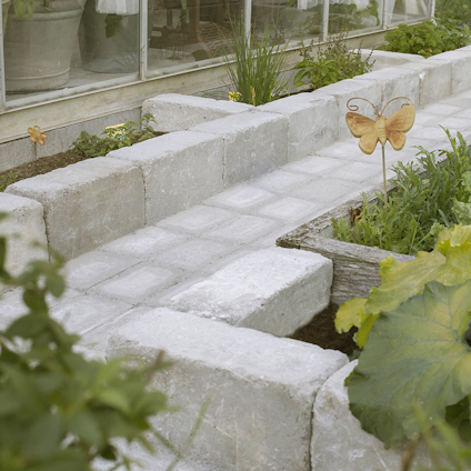Stenlagd gångväg omgiven av växter och en dekorativ fjäril i trädgårdsmiljö.